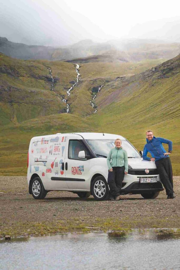 A couple standing by a fiat camoer in Iceland
