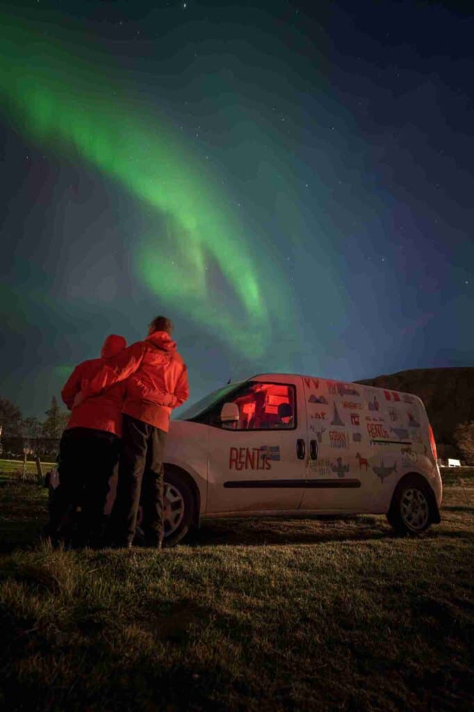 A couple and camper by northern lights