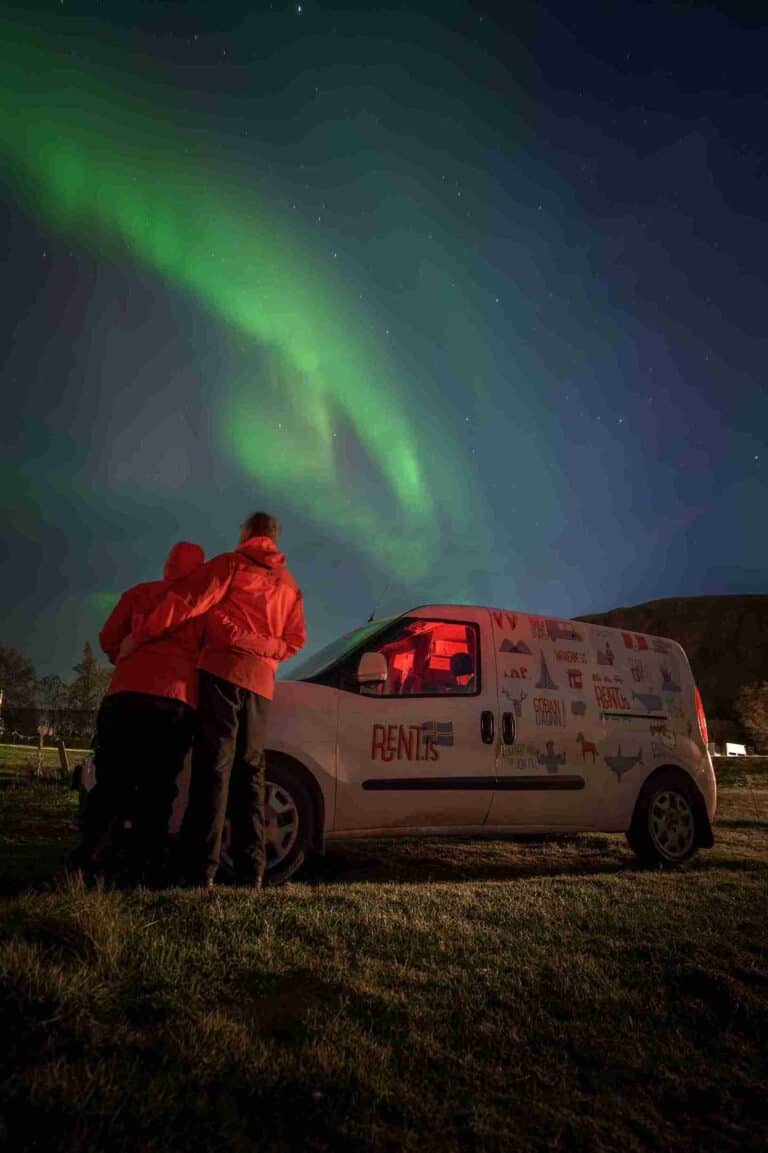 A couple and camper by northern lights