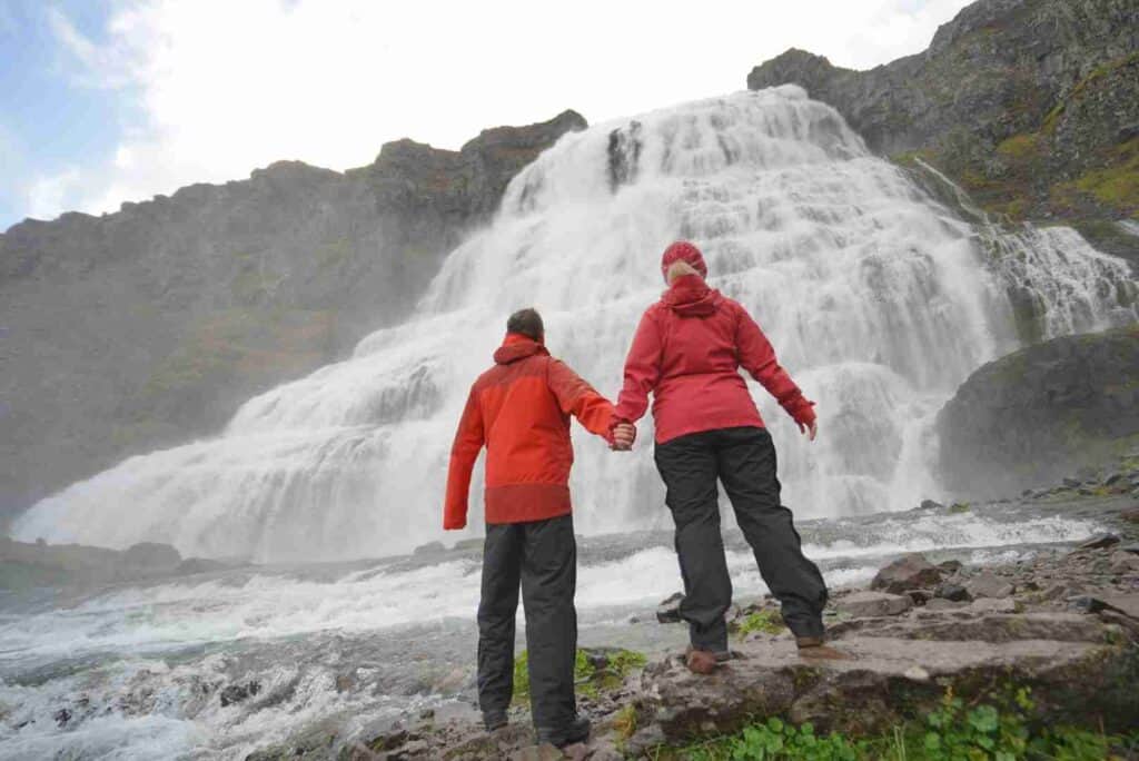 A couple holding hands by a waterfall
